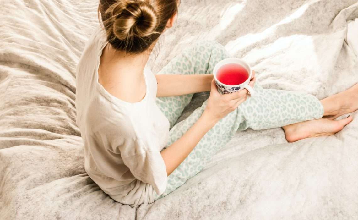 woman sat on bed with tea